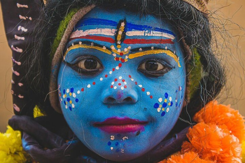 A person with blue face paint and colorful decorations. 4