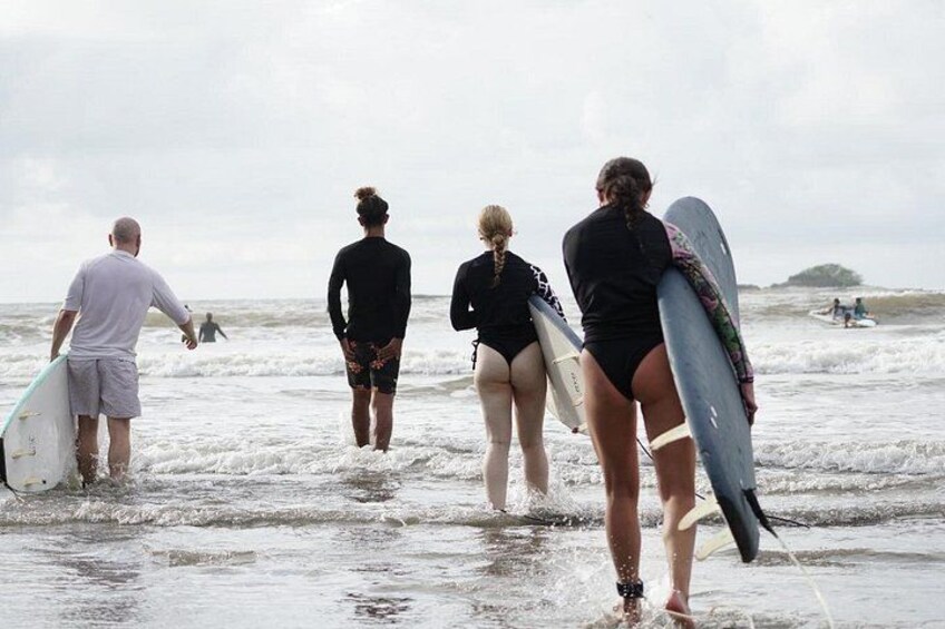 Eine Gruppe von Menschen geht mit Surfbrettern zum Meer. 1