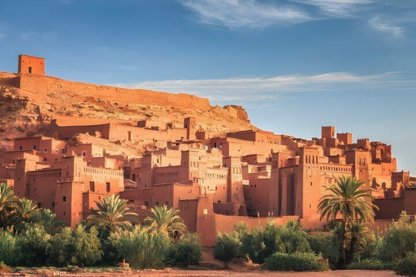 A desert town with adobe buildings, palm trees, and a hill with a watchtower. 1