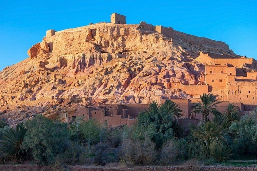 Una gran estructura de piedra antigua en la cima de una colina, rodeada de edificios más pequeños. 3