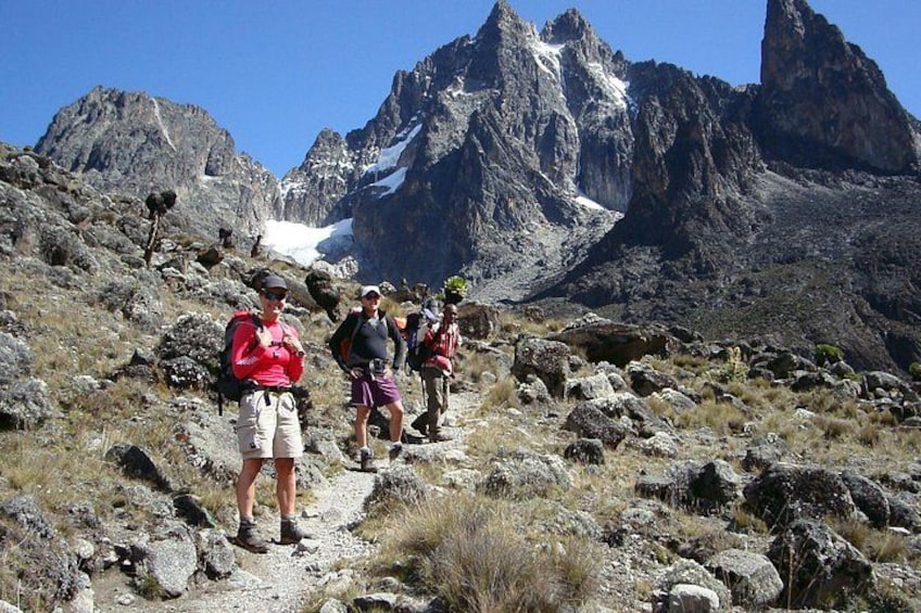 Hikers on a rocky trail with mountains in the background. 1