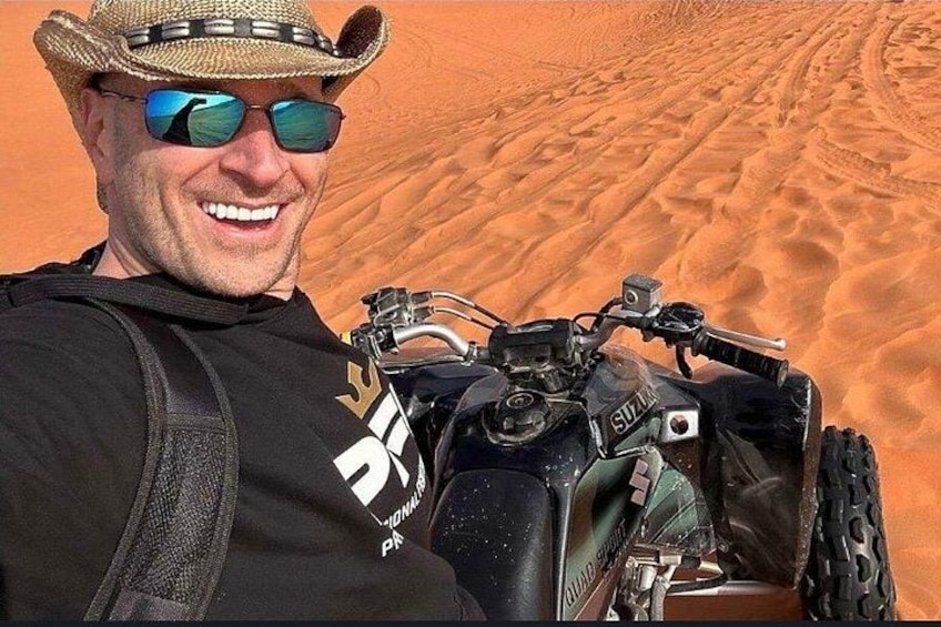 A person with a quad bike in a desert. 1
