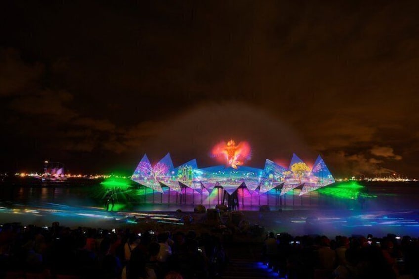 A nighttime outdoor light show with illuminated structures and water fountains. 2