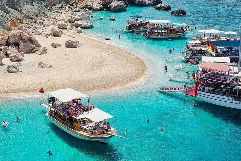 Un mar turquesa con barcos, una playa de arena y afloramientos rocosos. 2
