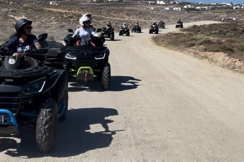 A group of people on ATVs on a dirt road in a rural area. 4