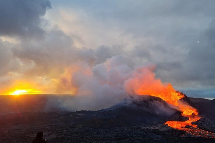 Une éruption volcanique avec de la lave qui coule le long du flanc d’une montagne au coucher du soleil. 1