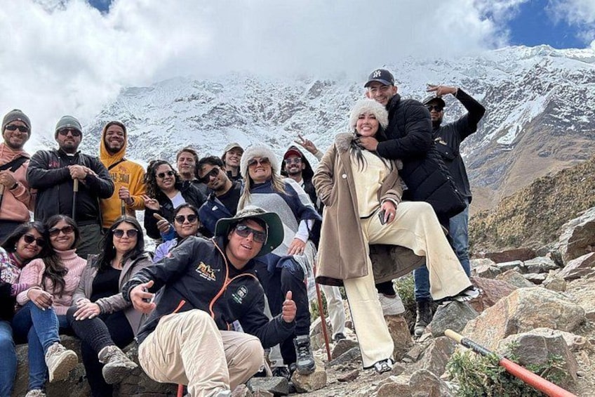 A group of people on a rocky mountain with snow-covered peaks in the background. 3