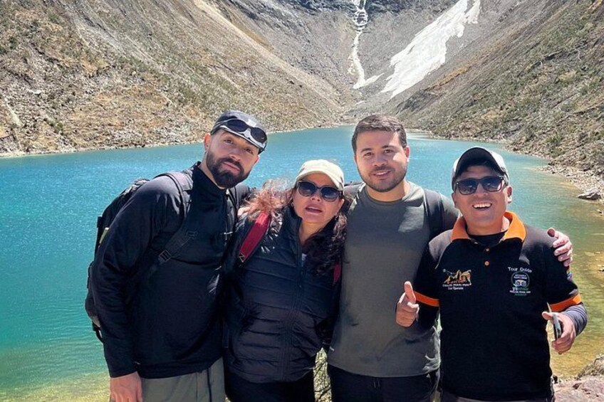 A group of people standing by a lake with a mountainous backdrop. 1