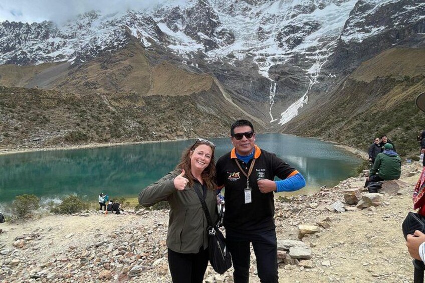 Two people standing by a lake with mountains in the background. 5