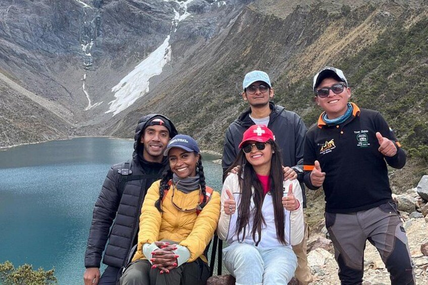 A group of people at a mountain lake with snow-capped peaks in the background. 2
