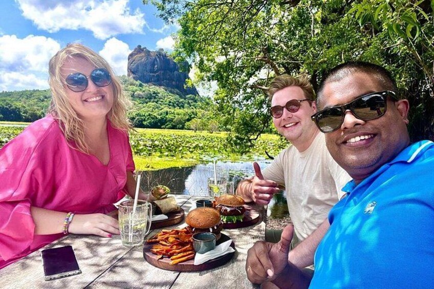 Three people dining outdoors with a scenic landscape in the background. 4