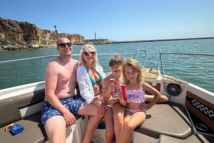 A family on a boat with rocky cliffs and a lighthouse in the background. 5