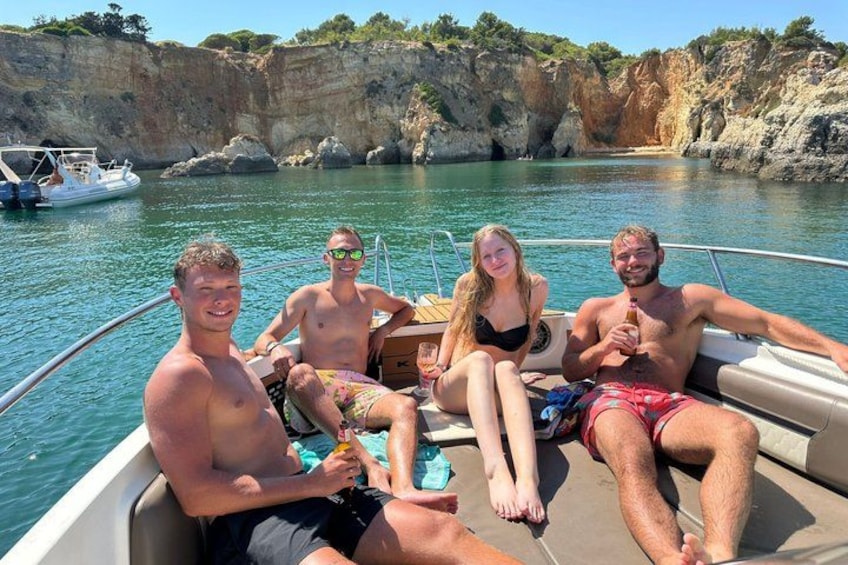 Een groep mensen op een boot op het water, met rotsachtige kliffen op de achtergrond. 3