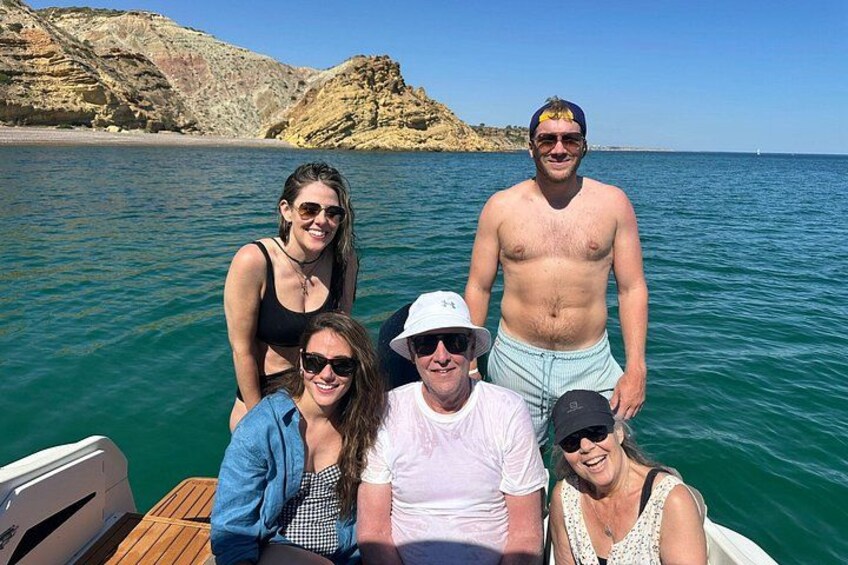 Un groupe de personnes se trouve à bord d’un bateau sur une étendue d’eau, avec un paysage rocheux en arrière-plan. 2