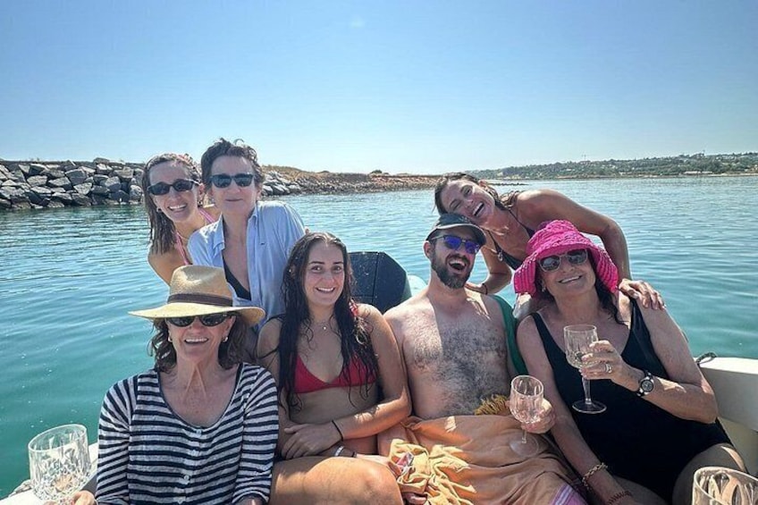 A group of people on a boat in a body of water with a rocky shoreline in the background. 4