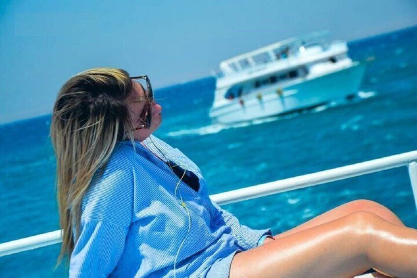Iemand zit op een boot, met een wit schip op de achtergrond. 5