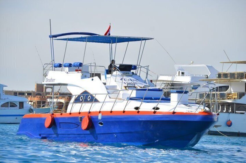 Een blauw en wit bootje met de naam 'Drafter' op de zijkant, drijvend op het water. 1