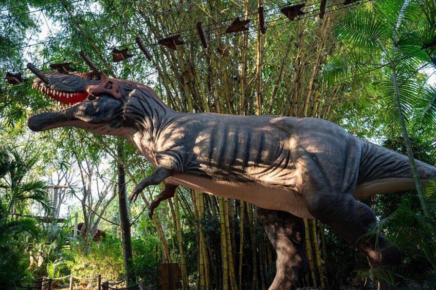 A life-sized Tyrannosaurus rex statue in a lush, green forest setting. 4