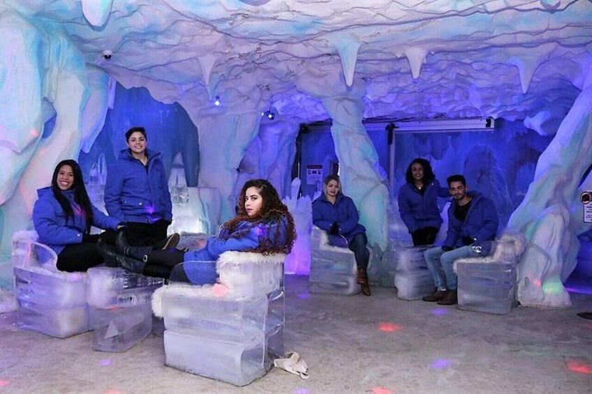 A group of people sitting on ice benches in an ice cave. 3