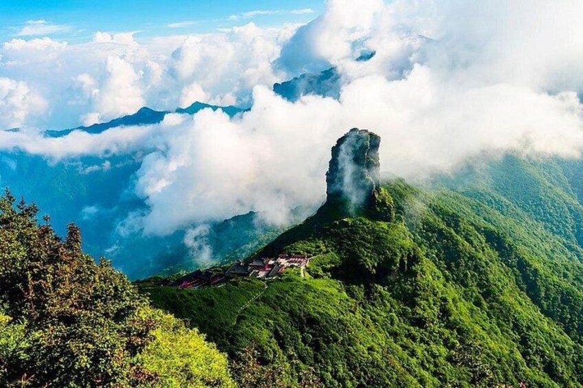 Un paisaje montañoso con una formación rocosa destacada, vegetación exuberante y un pueblo en el valle. 5