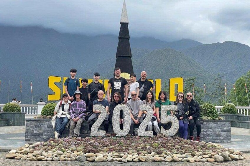 Un grupo de personas posando frente a un gran cartel con el año 2025. 2