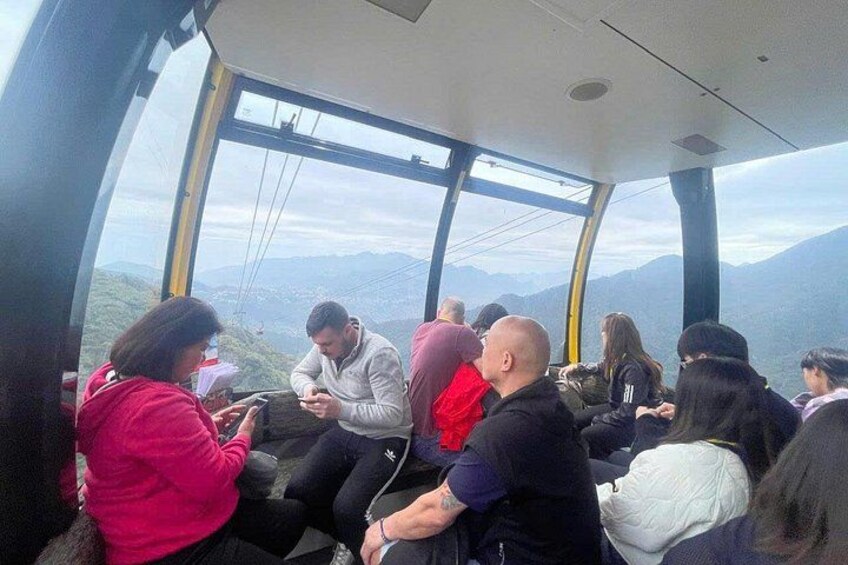 Personas sentadas dentro de un teleférico, observando un paisaje montañoso. 3