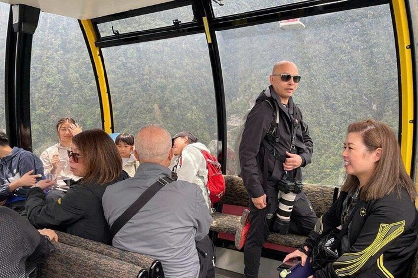 Un grupo de personas en un teleférico con un paisaje boscoso al fondo. 4