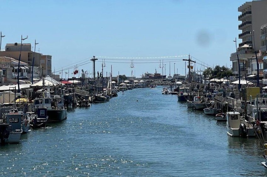 Una marina con imbarcazioni ormeggiate lungo un canale tranquillo, circondata da edifici. 1