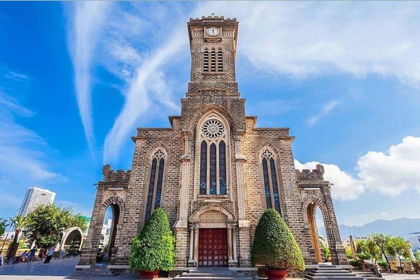 Een historisch kerkgebouw met een hoge toren, brede gotische ramen en een rode deur. 1