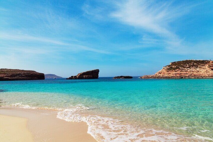 Una playa con agua turquesa cristalina, arena dorada y formaciones rocosas. 4