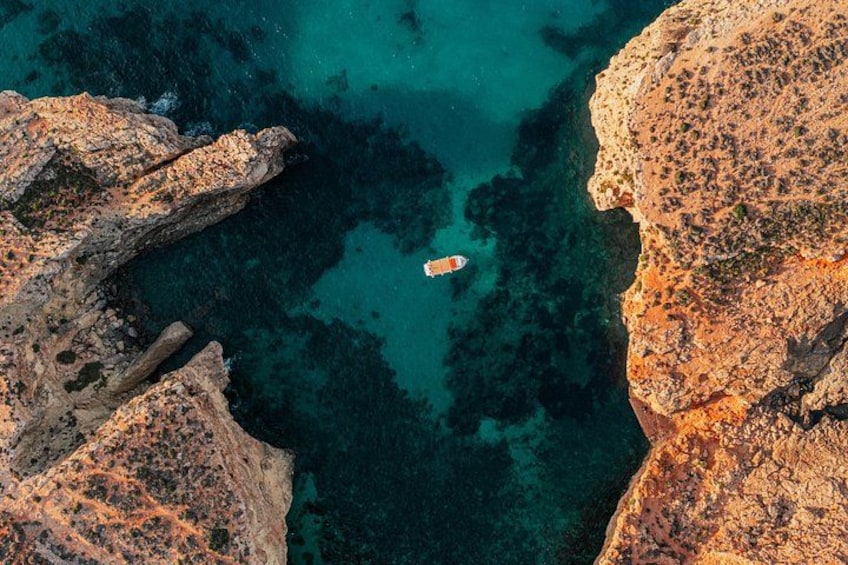 A rocky coastline with clear turquoise waters and a small boat. 3