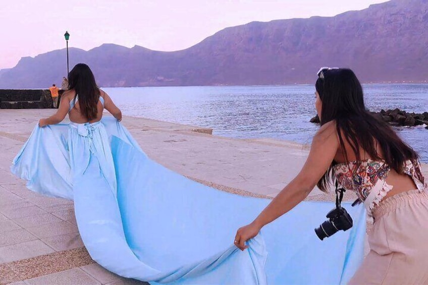 A person in a light blue dress being photographed by another person with a camera. 5