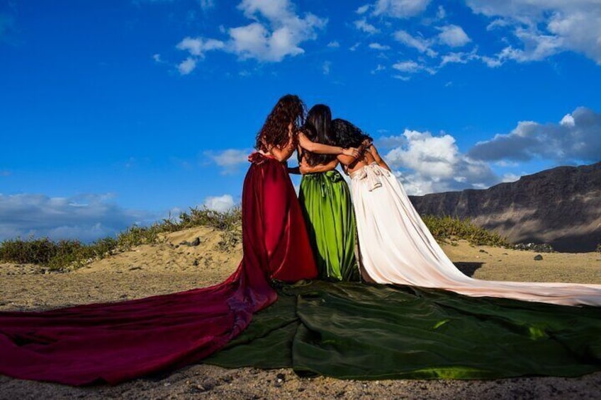 Three figures in flowing robes sitting on a blanket in a desert landscape. 2