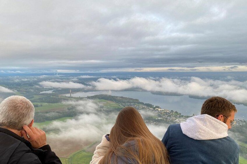 Tre personer ser ud over et landskab med skyer og et fjerntliggende vand. 2