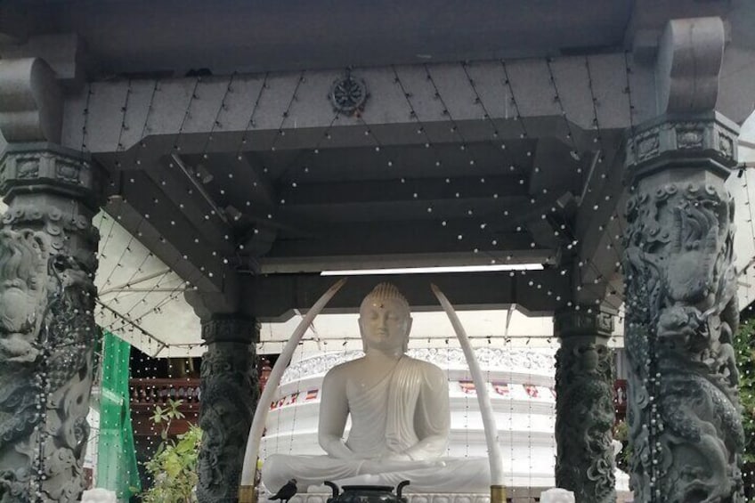 Una gran estatua de Buda bajo un pabellón cubierto con intrincados relieves y un techo decorativo. 2
