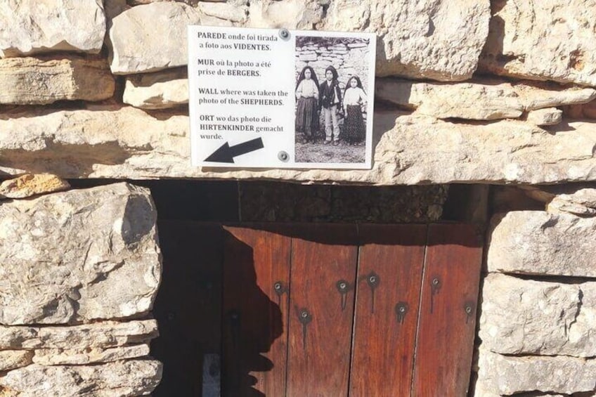 A stone wall with a wooden door and a sign with a photo and text. 3