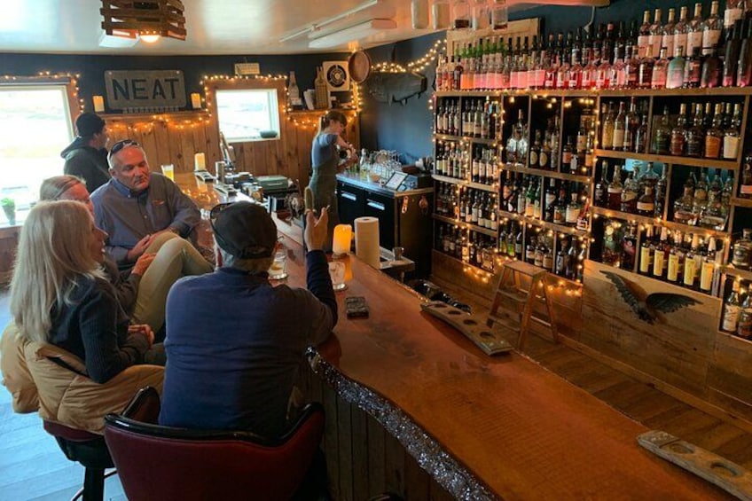 A bar with people sitting and a bartender serving drinks. 2