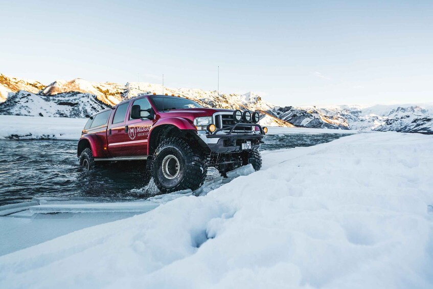 A red pickup truck driving through a snowy landscape with mountains in the background. 5