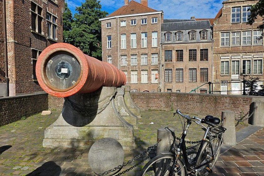 A cannon, a bicycle, and a brick building in the background. 5