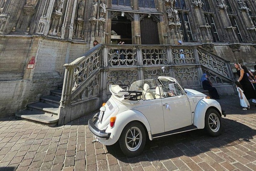 A white convertible car parked in front of a historic building with ornate architecture. 2