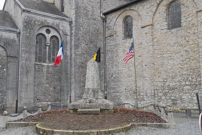 En bygning i sten med flagstang, et fransk flag og et amerikansk flag. 3