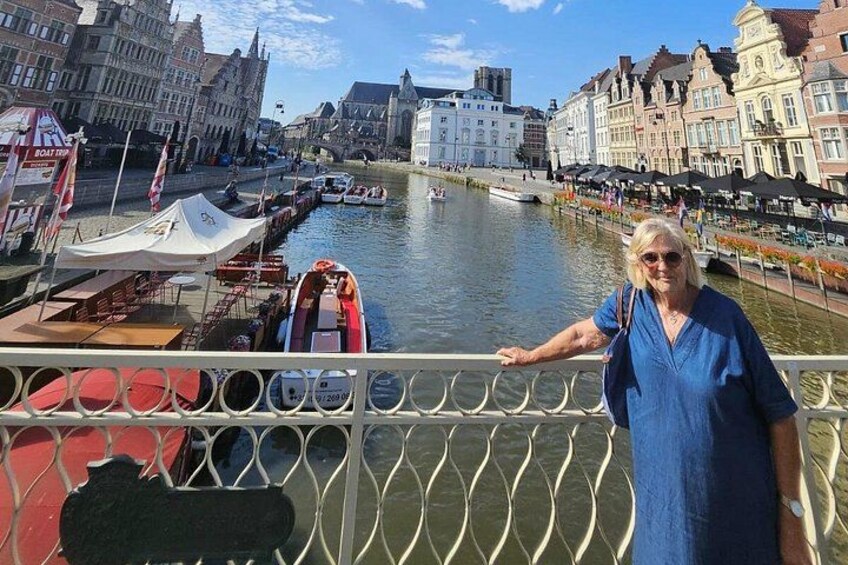 A person standing on a bridge with a river and buildings in the background. 3