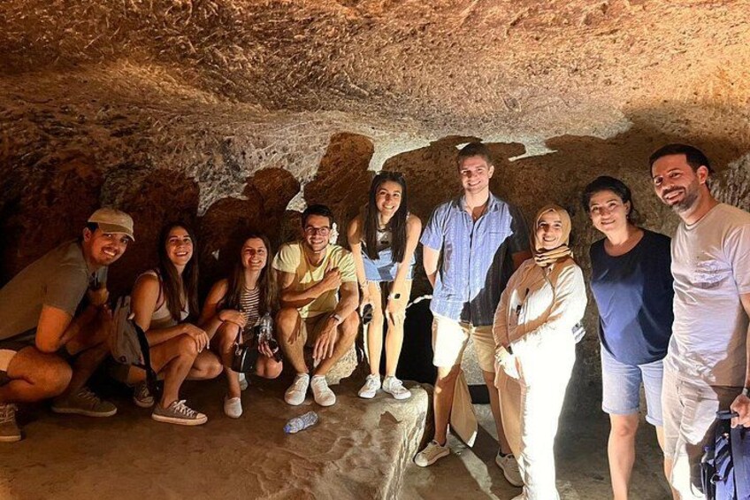 A group of people inside a cave with rocky walls and a flat floor. 4