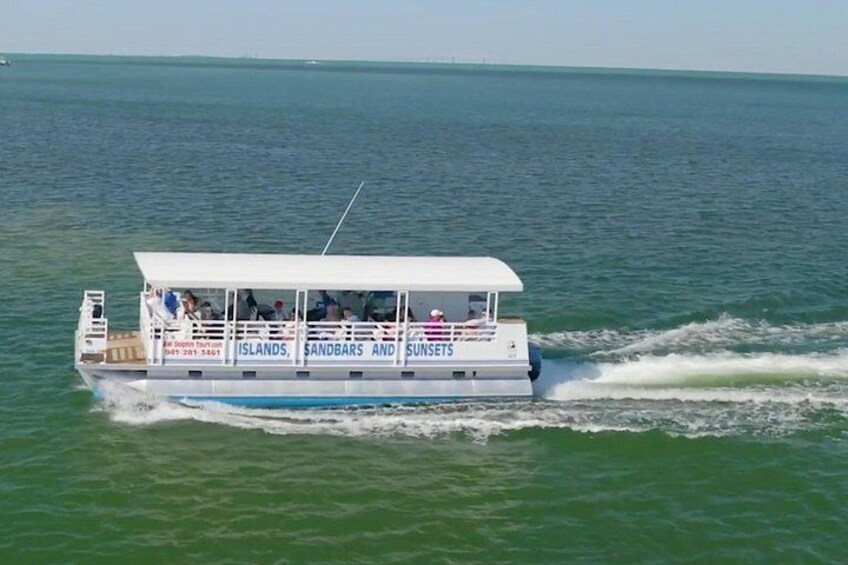 A boat with 'ISLANDS, SUNSETS' written on its side, moving through the water. 2