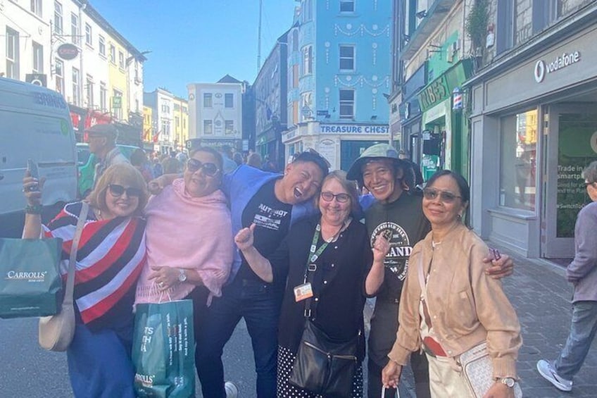 Un grupo de personas posando en una calle de la ciudad, con tiendas y un edificio azul al fondo. 3