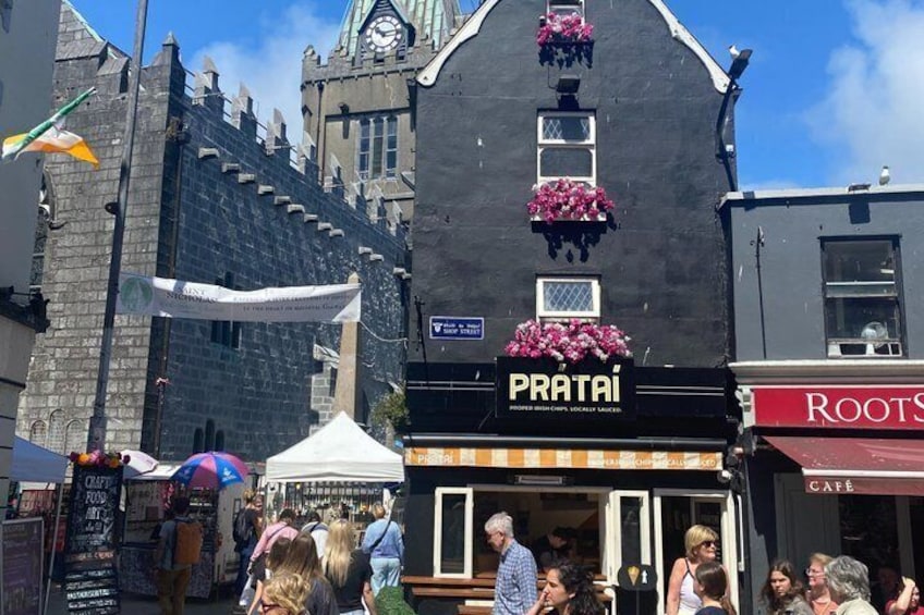 Un edificio negro con un letrero que dice 'PRATAI' y un café llamado 'ROOTS' a la derecha. 2