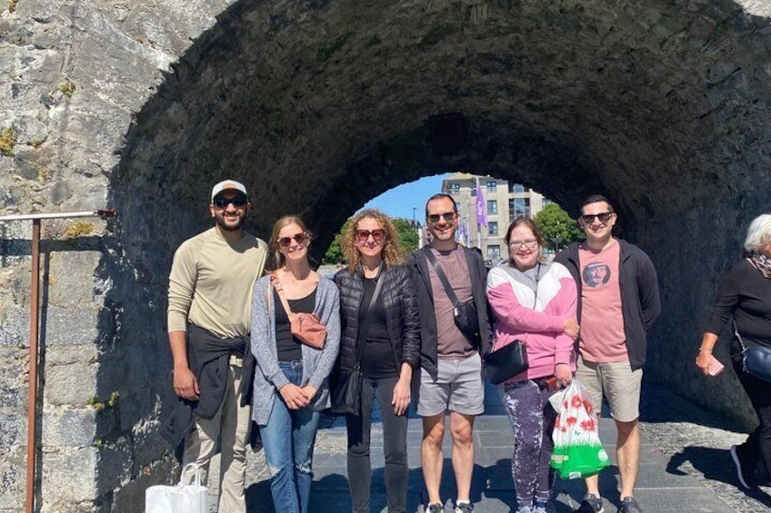 Un grupo de personas de pie frente a un arco de piedra. 5