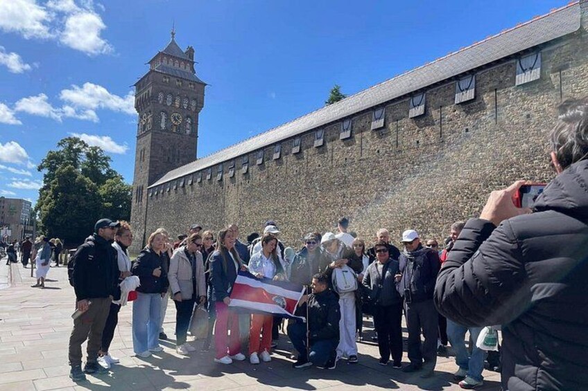 Una multitud de personas se ha reunido frente a un edificio histórico de piedra con una torre del reloj. 1