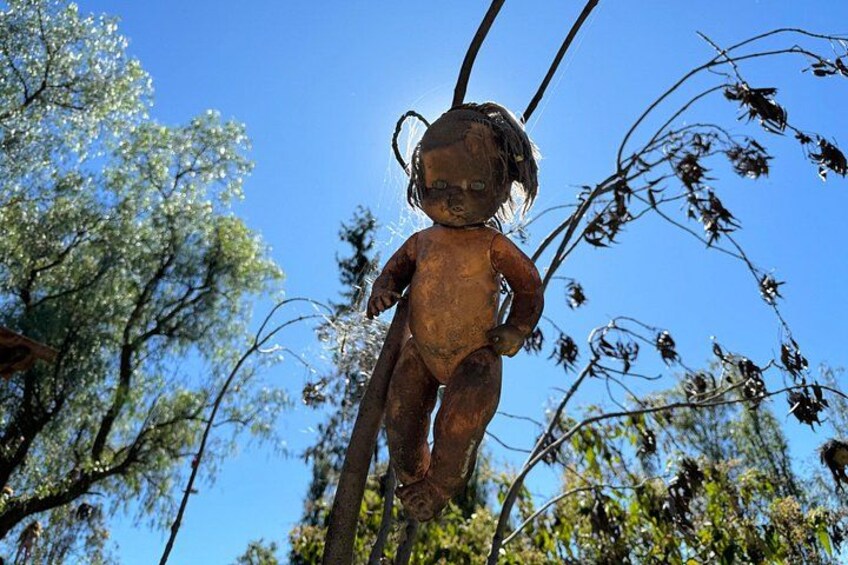 Una statua scolpita dal tempo raffigura un bambino immerso nella natura, con alberi e cielo sereno. 3