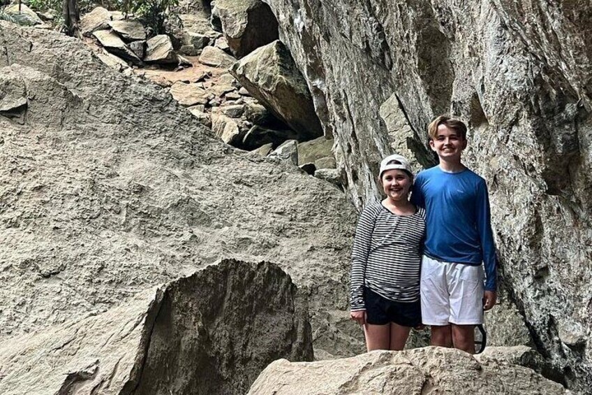 Two people standing on a rocky terrain with a large rock formation in the background. 5